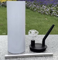 a white glass pipe and a black pipe on a grassy area